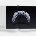 Libro PlayStation: The First 30 Years abierto por una fotografía del prototipo de mando bumerán de PS3