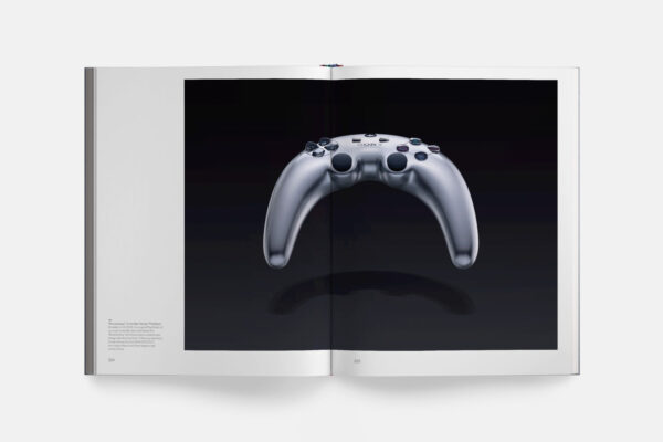 Libro PlayStation: The First 30 Years abierto por una fotografía del prototipo de mando bumerán de PS3