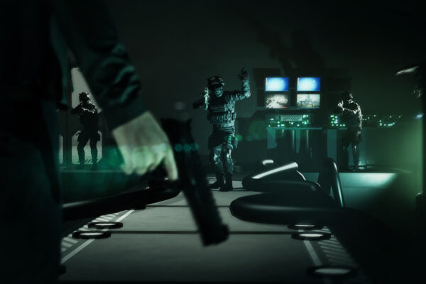 Un personaje sostiene un arma mientras varias figuras se acercan entre los equipos de una instalación de SCP: Project Pneuma