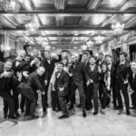El equipo de Sabotage Studio, vestido de gala, celebra su décimo aniversario en una fotografía en blanco y negro.